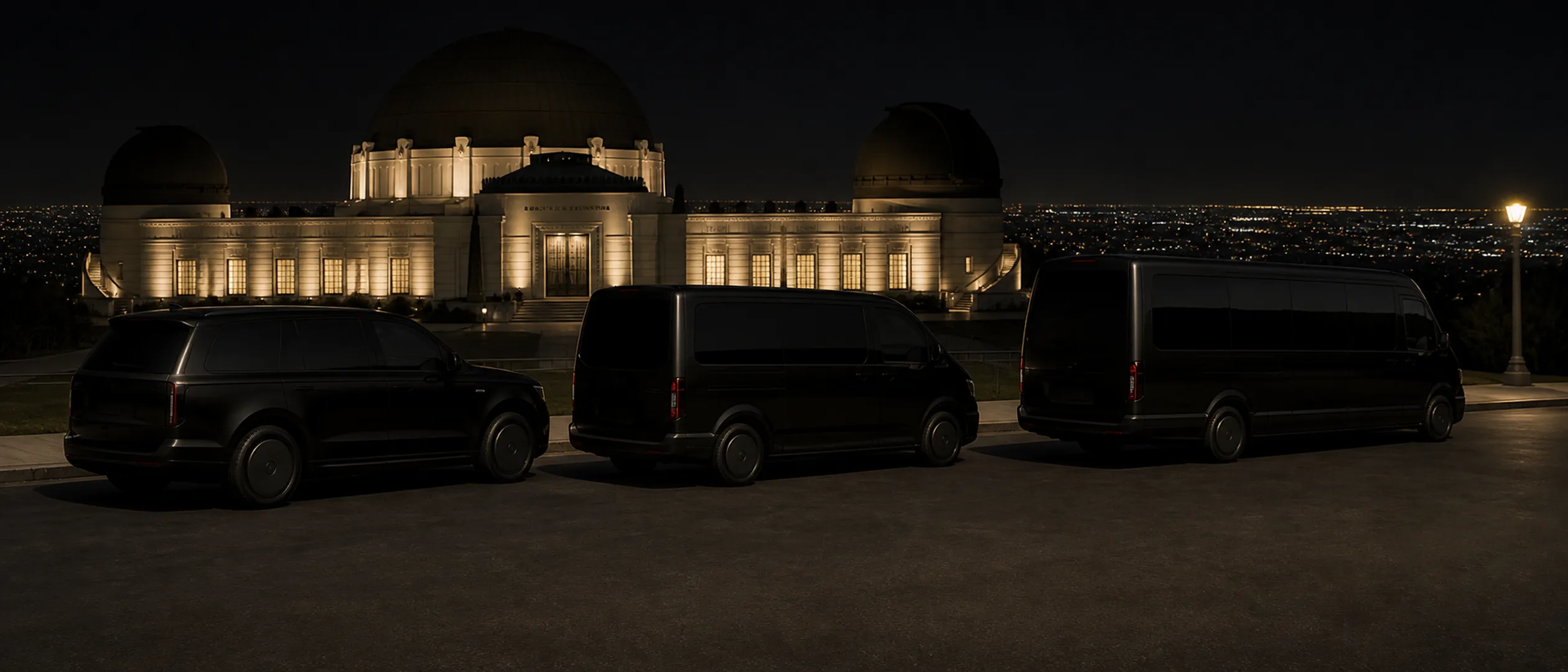 Three black vehicles are parked side by side at a shallow angle below Griffith Observatory.
