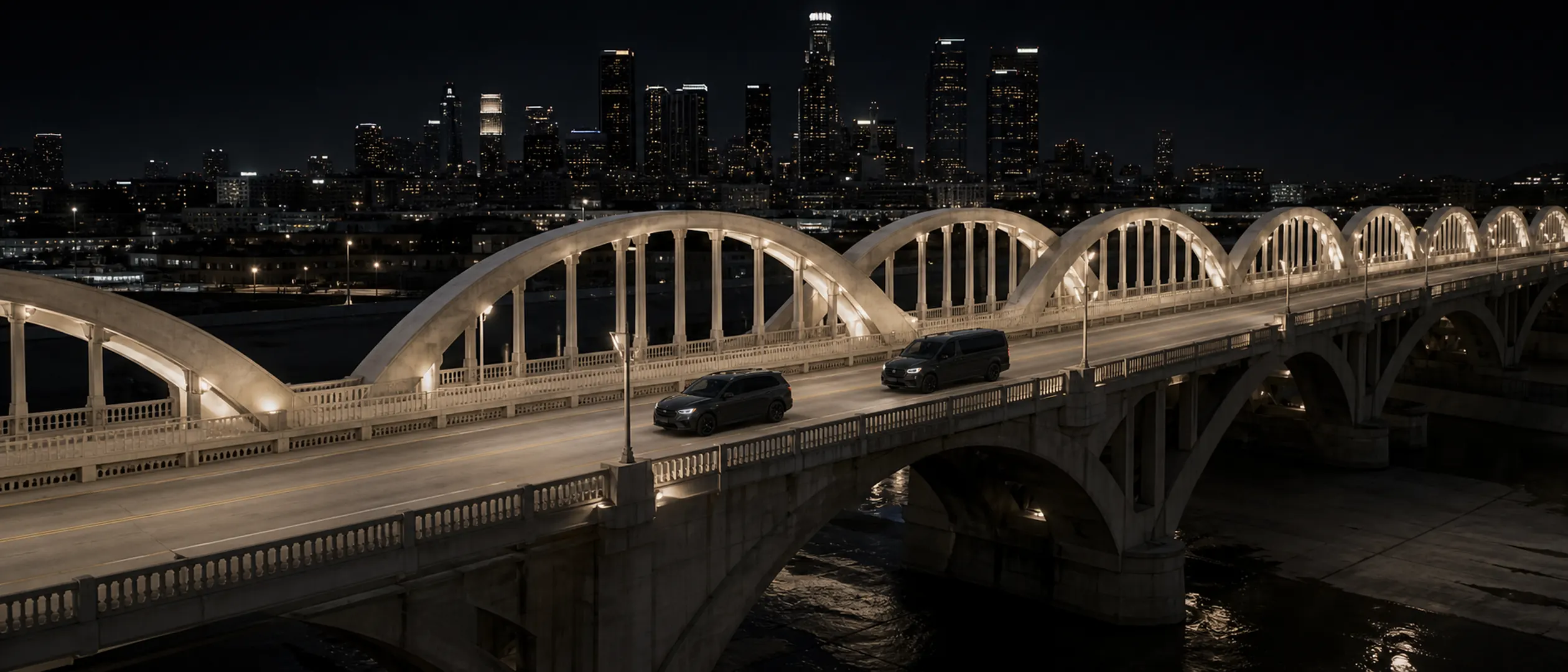 A black SUV leads a black passenger van across the Sixth Street Viaduct in Los Angeles.